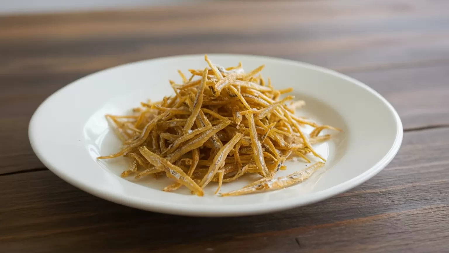 small fried anchovies on a white plate